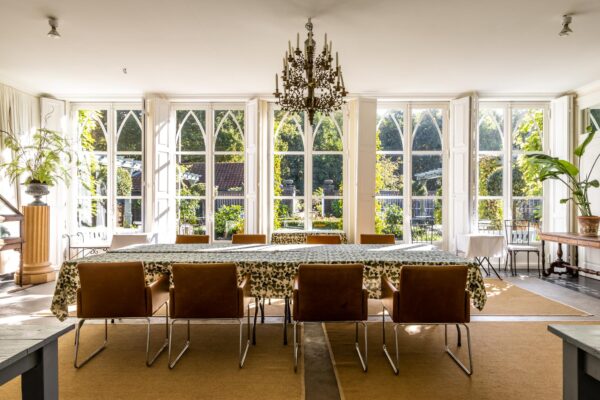 Stijlvolle eetruimte aan de Langbroekerdijk met grote ramen, een lange tafel met bladmotief en uitzicht op een groene tuin.